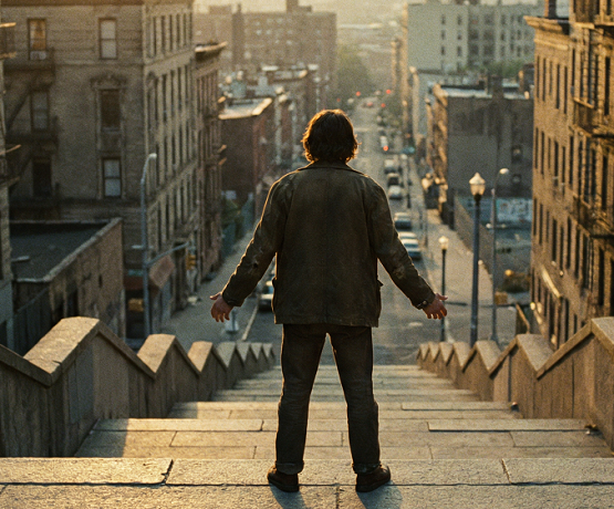 Performer steht oben an einer langen Treppe
im Goldstunden-Licht. Nicht tanzend Körperspannung