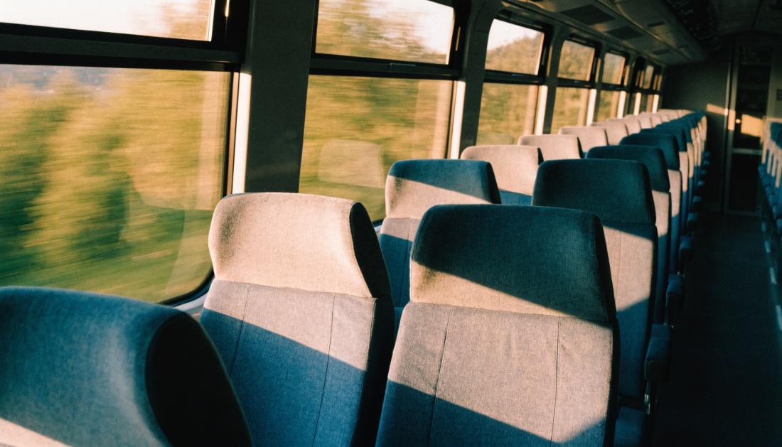 Leere Sitzreihen in einem Fernverkehrszug, tief stehende Abendsonne f&auml;llt durch die Fenster