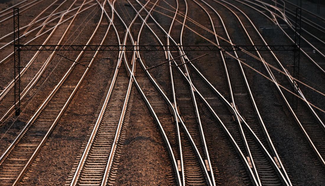 Blick von oben auf viele parallele Gleise, die sich vor einem Bahnhof auffaechern