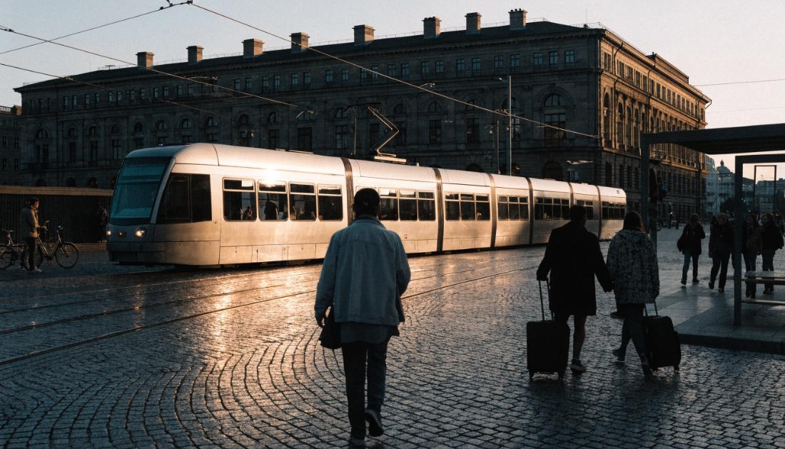 Eine Strassenbahn faehrt ueber den Platz vor einem grossen Bahnhofsgebaeude