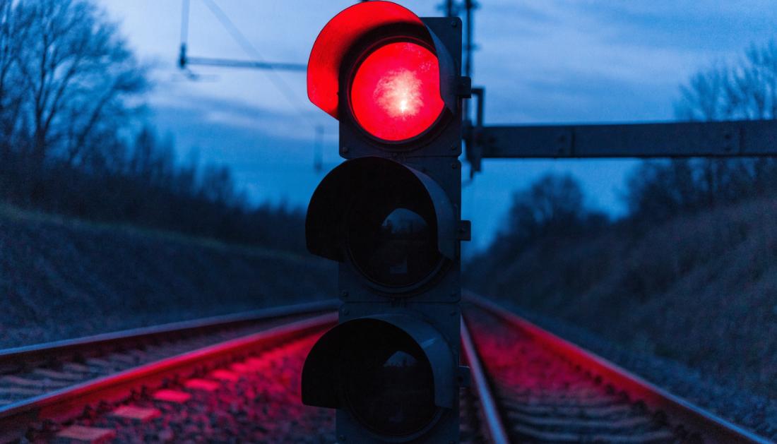Ein Eisenbahn-Lichtsignal zeigt Rot vor tiefblauem Daemmerungshimmel