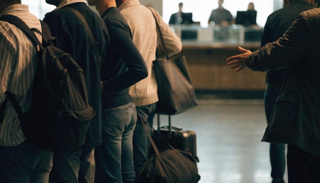 Gestrandete Reisende mit Gepaeck stehen vor einem Servicecounter im Bahnhof