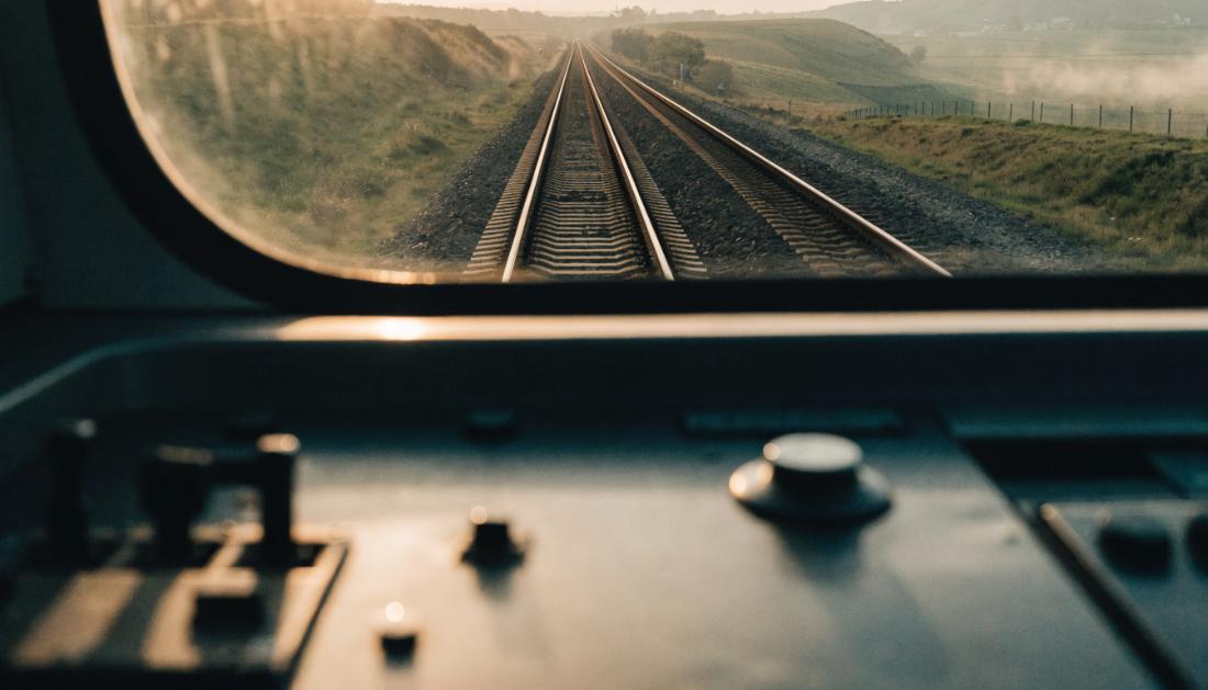 Blick durch die Frontscheibe eines Fuehrerstands auf die Strecke im Morgenlicht
