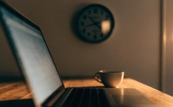Laptop und Uhr auf einem Schreibtisch im warmen Abendlicht