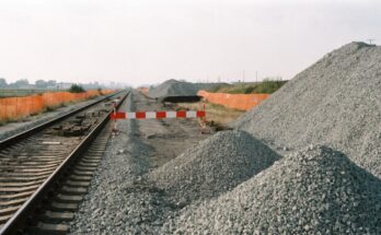Eine gesperrte Bahnstrecke mit rot-weisser Schranke, Bauzaun und frischem Schotter