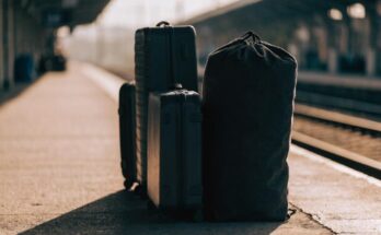 Mehrere Koffer und eine Reisetasche stehen im Morgenlicht auf einem Bahnsteig