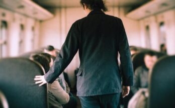 Ein Zugbegleiter in dunkler Uniform geht durch den Mittelgang eines Wagens