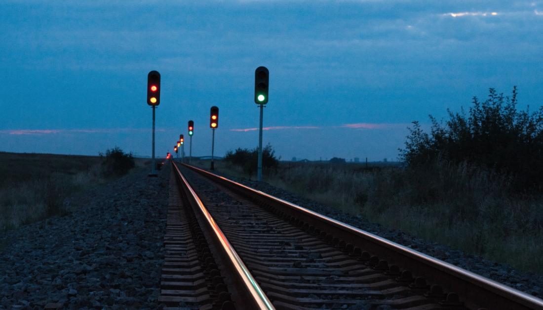 Mehrere Lichtsignale stehen in regelm&auml;&szlig;igen Abst&auml;nden entlang einer Bahnstrecke