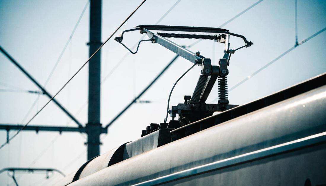 Angehobener Stromabnehmer auf dem Dach eines Zuges liegt am Fahrdraht an
