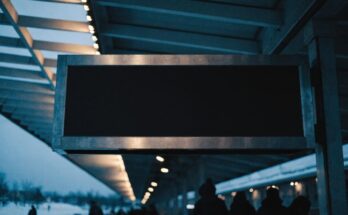 Grosse dunkle Anzeigetafel unter einem Bahnhofsdach im Winterlicht
