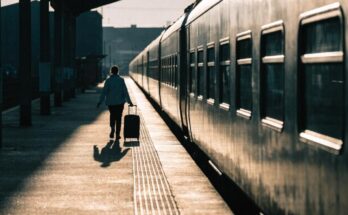 Ein Reisender mit kleinem Koffer geht zuegig am Bahnsteig entlang