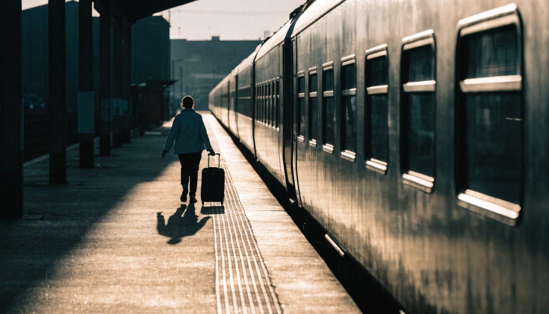 Ein Reisender mit kleinem Koffer geht z&uuml;gig am Bahnsteig entlang