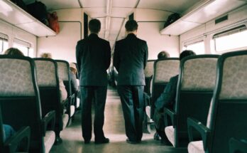 Zwei Kontrolleure in dunkler Kleidung stehen im Mittelgang eines Regionalzuges
