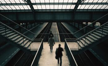 Eine breite Fussgaengerbruecke mit Treppen hinunter zu mehreren Bahnsteigen