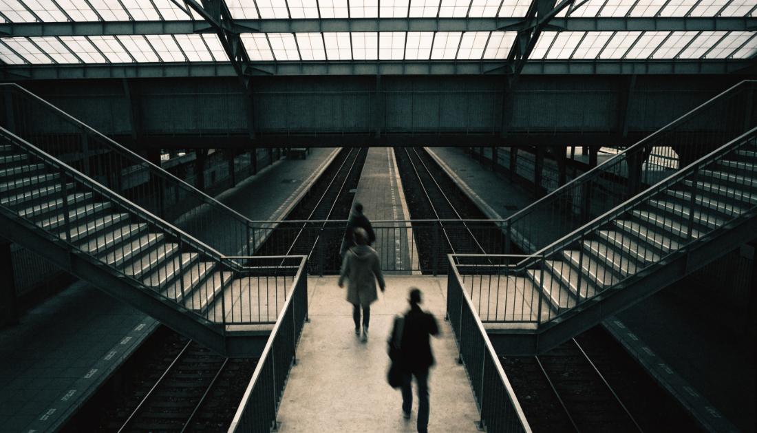 Eine breite Fu&szlig;g&auml;ngerbr&uuml;cke mit Treppen hinunter zu mehreren Bahnsteigen