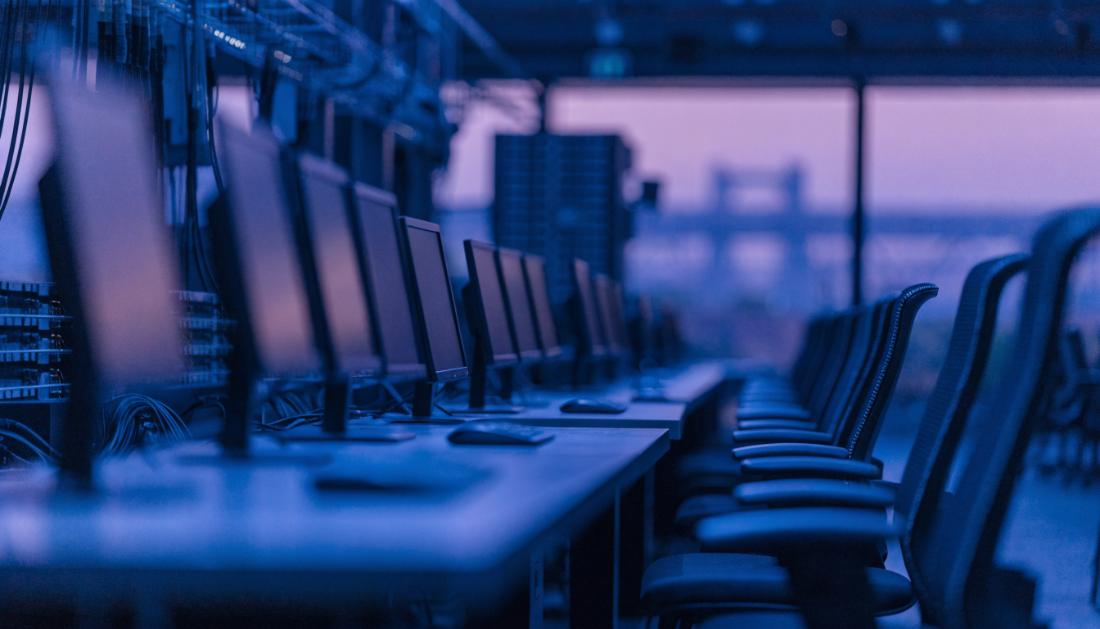 Dunkle Bildschirme und leere Arbeitspl&auml;tze in einer modernen Betriebszentrale