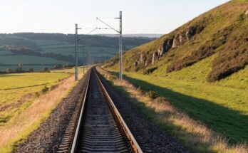 Ein letzter Oberleitungsmast steht am Ende der elektrifizierten Strecke, die Gleise laufen weiter ins Gruene