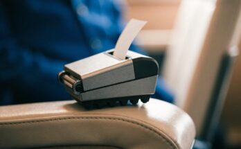 Ein kleines mobiles Fahrscheindruckgeraet liegt auf einer Zugsitzlehne