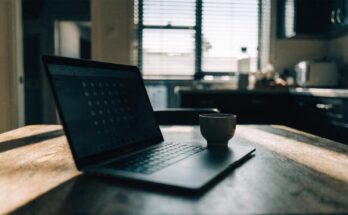 Ein Laptop auf einem Kuechentisch zeigt eine unscharfe Buchungsmaske mit leuchtenden Kalenderpunkten