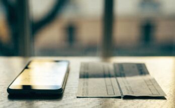 Ein Smartphone mit einer unscharfen Stornobestaetigung liegt neben einer gedruckten Fahrkarte