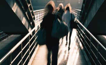 Reisende ueberqueren eilig eine Fussgaengerbruecke zwischen zwei Bahnsteigen