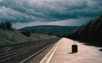 Ein einzelner Koffer steht verlassen auf einem leeren Bahnsteig unter stuermischem Himmel