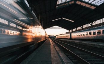 Zwei Zuege stehen an gegenueberliegenden Bahnsteigen, einer faehrt in Bewegungsunschaerfe ab