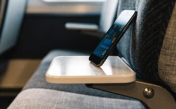 Ein Smartphone auf einem Zugtisch zeigt eine unscharfe Stoerungs-App mit farbigen Warnsymbolen