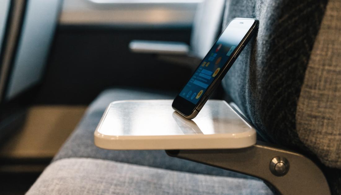 Ein Smartphone auf einem Zugtisch zeigt eine unscharfe Stoerungs-App mit farbigen Warnsymbolen