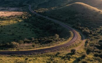 Ein Bahngleis schwingt sichtbar geneigt durch eine Kurve in der Landschaft