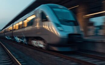 Ein Zug bremst bei der Einfahrt in einen Bahnhof mit symbolischem blauem Lichtschein an den Raedern