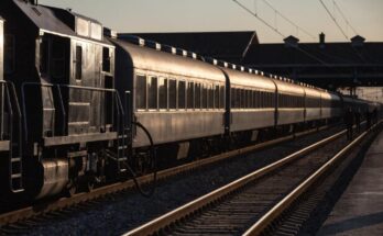 Eine Lokomotive wird von einer Wagenreihe abgekuppelt, im Hintergrund Silhouetten von Arbeitern