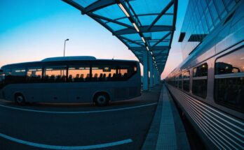 Ein Fernbus und ein Zug stehen nebeneinander an einem modernen Verkehrsknotenpunkt