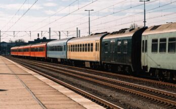 Mehrere unterschiedlich lackierte Regionalzuege stehen nebeneinander an einem grossen Bahnsteig