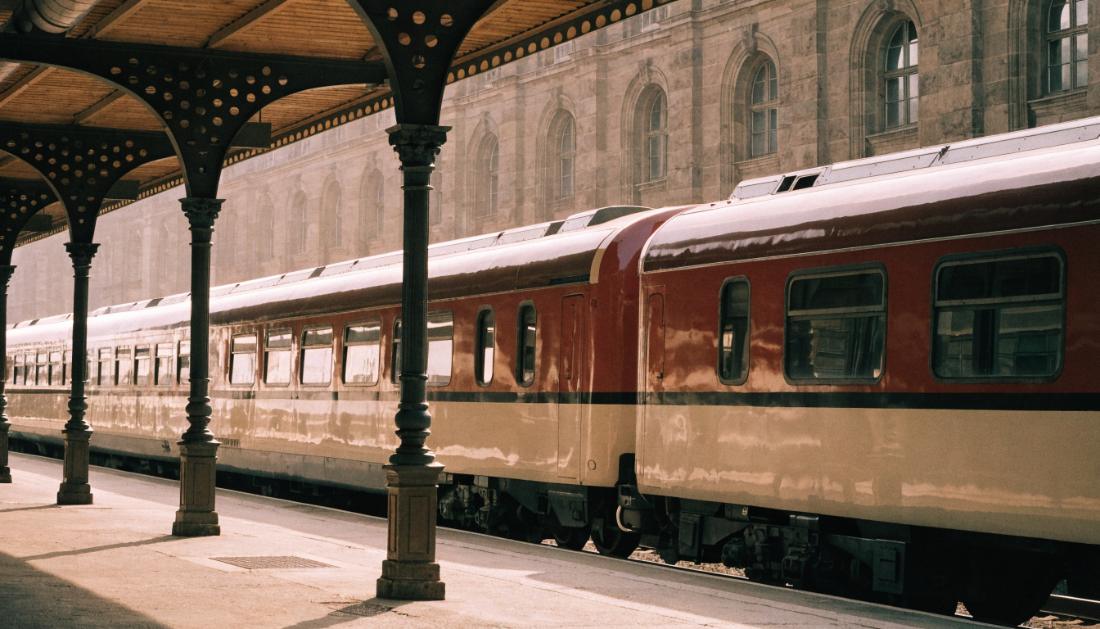 Ein eleganter Diesel-Expresszug im nostalgischen Stil steht an einem grossen europaeischen Bahnhof