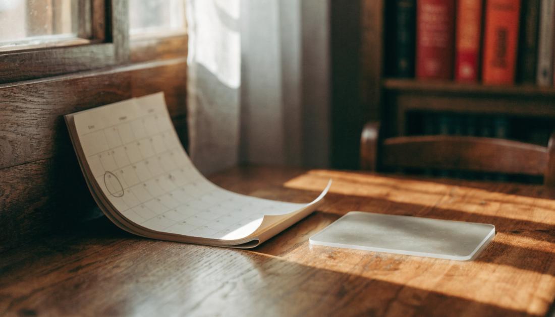 Ein Wandkalender mit eingekreistem Datum neben einer unbeschrifteten Plastikkarte auf einem Schreibtisch