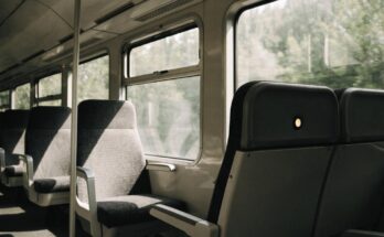 Ein halb besetzter Zugwagen bei Tageslicht mit einer leuchtenden Reservierungsanzeige über einem Sitz