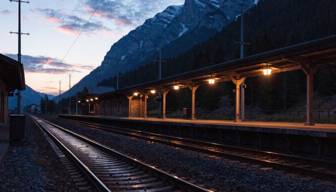 Ein alpiner Grenzbahnhof in der Abenddämmerung mit Bergen im Hintergrund