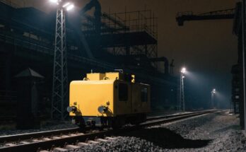 Ein kleines gelbes Wartungsfahrzeug steht nachts unter Flutlicht auf einem Gleis