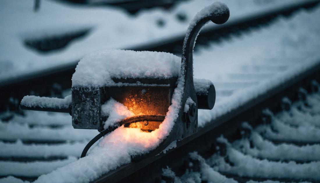 Eine schneebedeckte Weiche mit sichtbarem warmen Schein, der den Schnee ringsherum schmilzt