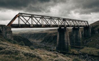 Eine alte verwitterte Eisenbahnbrücke mit sichtbarem Rost unter bewölktem Himmel