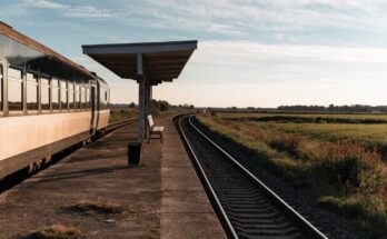 Ein kleiner ländlicher Bahnsteig inmitten offener Landschaft mit einem wartenden Regionalzug