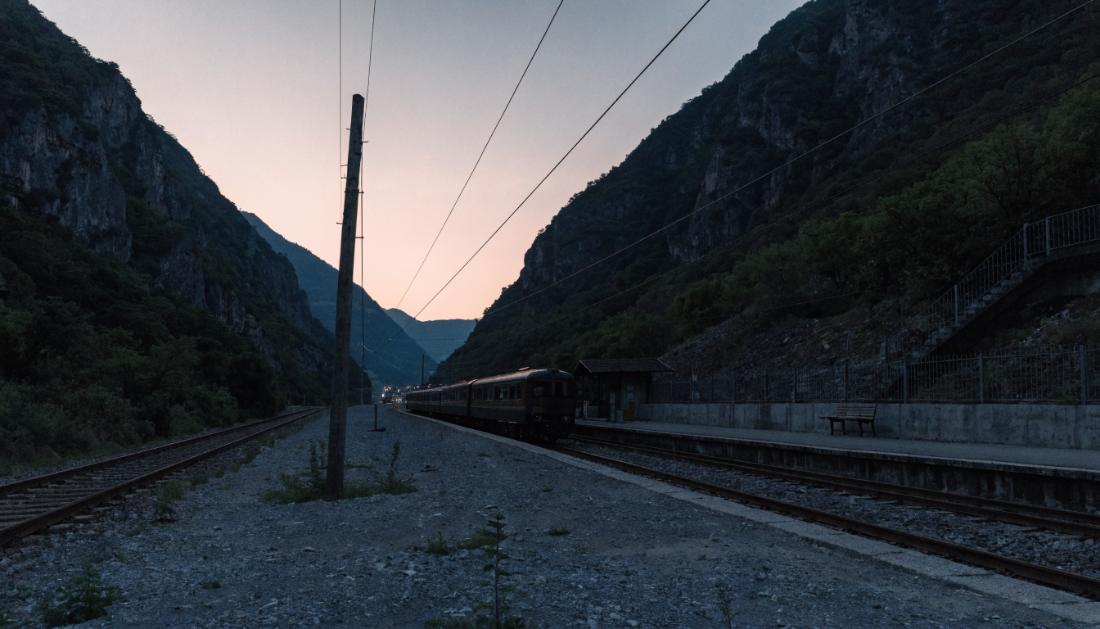 Ein ruhiger Grenzbahnhof in einem Bergtal in der Abenddämmerung mit einem stehenden Zug