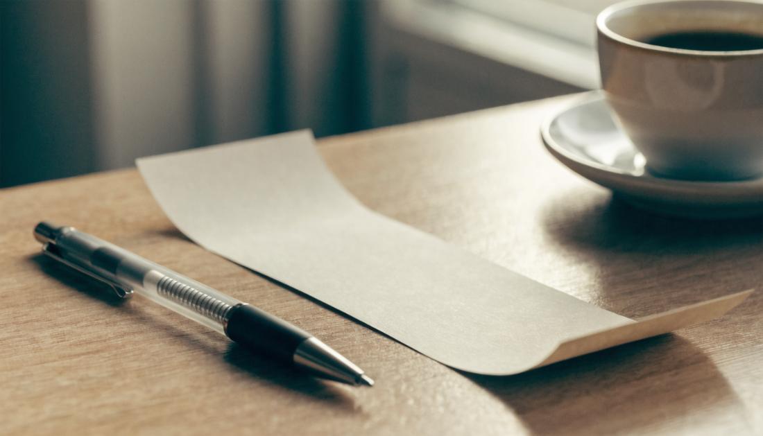 Ein schlichtes Papierticket liegt auf einem Schreibtisch neben Stift und Kaffeetasse