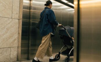 Ein Elternteil schiebt einen Kinderwagen in einen Bahnhofsaufzug