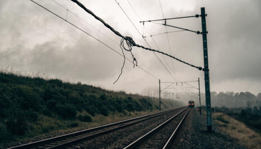 Ein beschädigter Oberleitungsdraht hängt lose über Bahngleisen