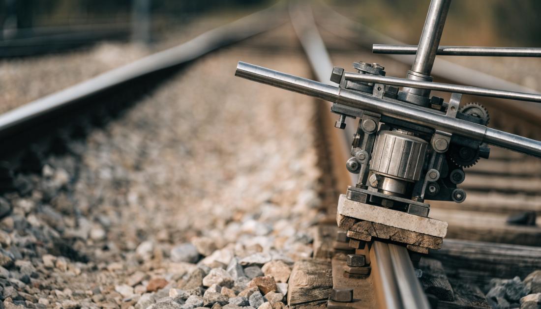 Nahaufnahme eines Weichenmechanismus mit sichtbaren Stahlstangen und Motoreinheit neben den Schienen