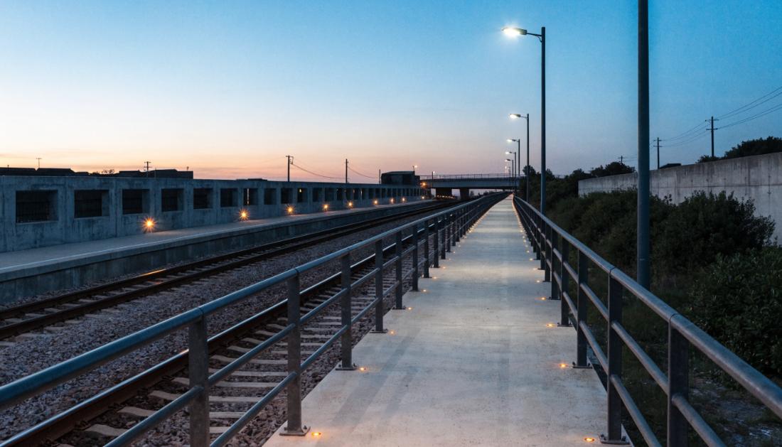 Ein Rettungsweg neben Bahngleisen mit Sicherheitsbeleuchtung in der Dämmerung
