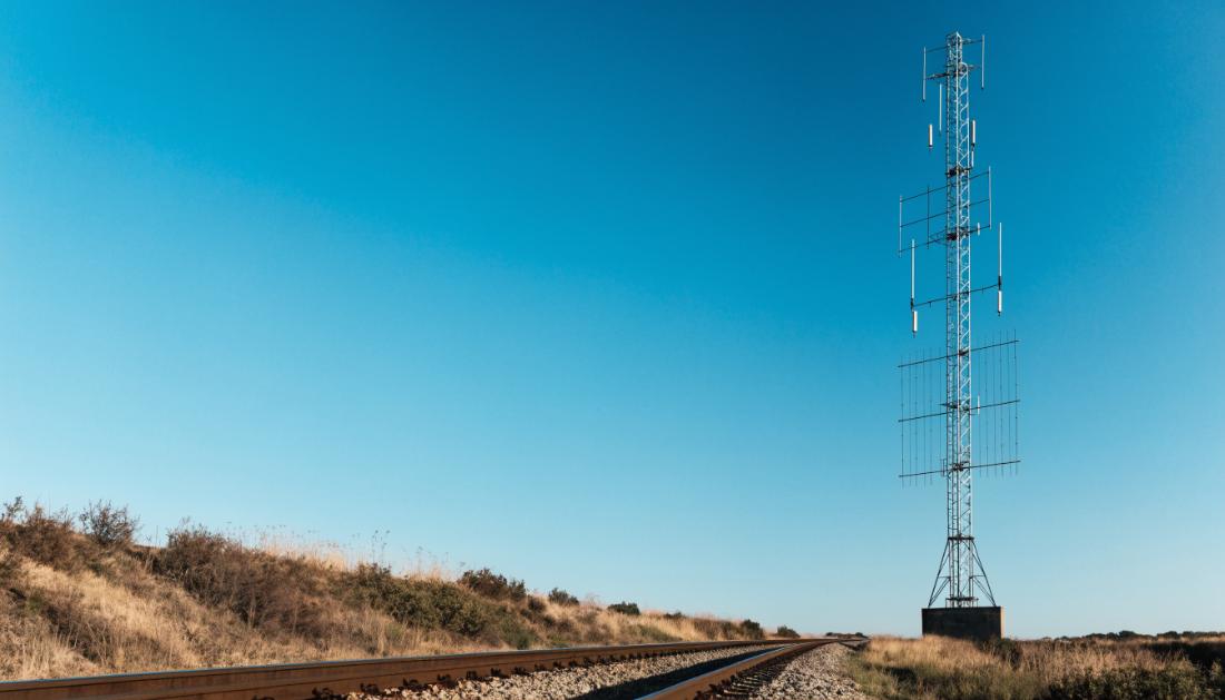 Ein Funkmast neben Bahngleisen vor weitem offenem Himmel