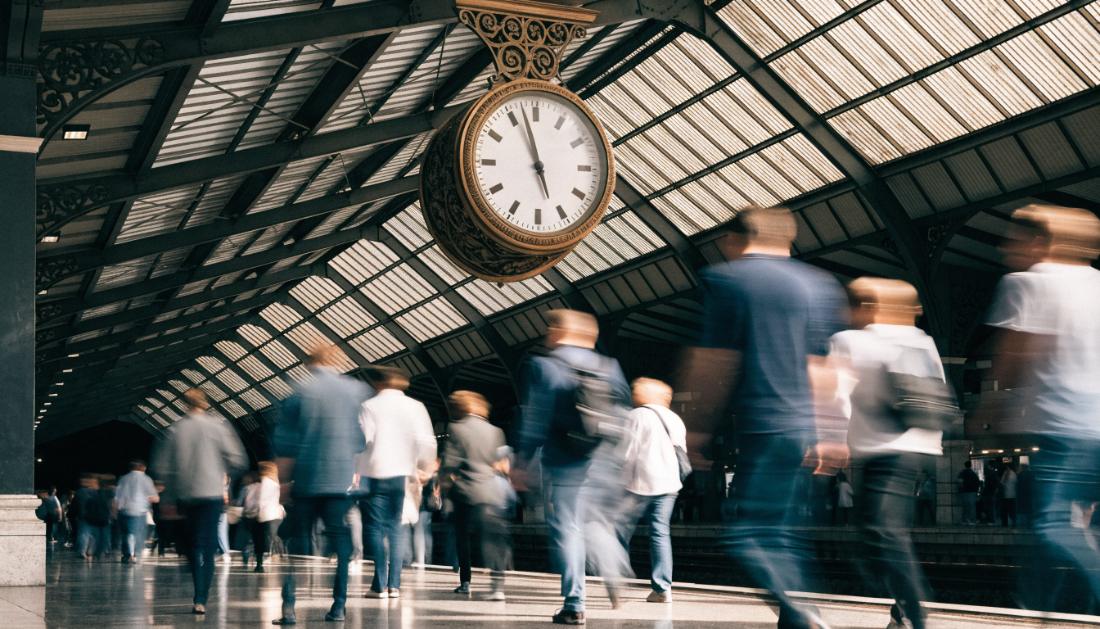 Eine große Bahnhofsuhr über einem belebten Bahnsteig